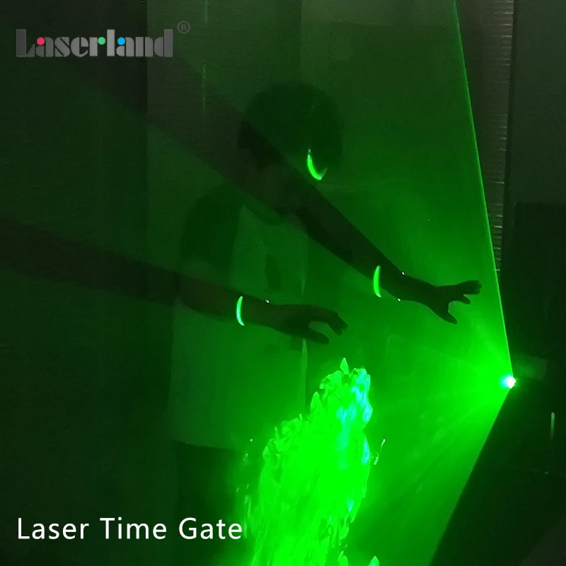 A green laser beam cuts through the air, illuminating a silhouette of a person and a burst of green light.