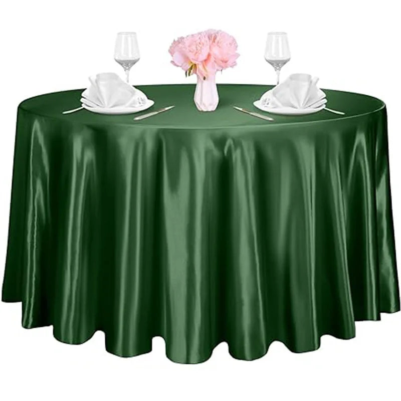 A dark green satin tablecloth set for an elegant table with pink flowers and glassware.