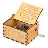 A vintage hand-cranked wooden music box with an open lid and engraved text inside.