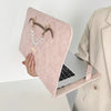 A pink water-resistant laptop briefcase with a leather strap and pearl necklace is shown next to an open laptop.