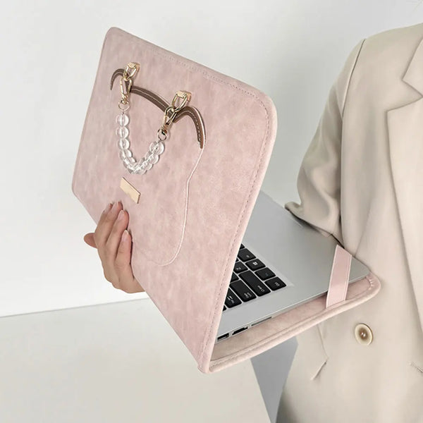 A pink water-resistant laptop briefcase with a leather strap and pearl necklace is shown next to an open laptop.