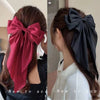 A woman shows off a deep red silk bow hair clip tied in her hair.