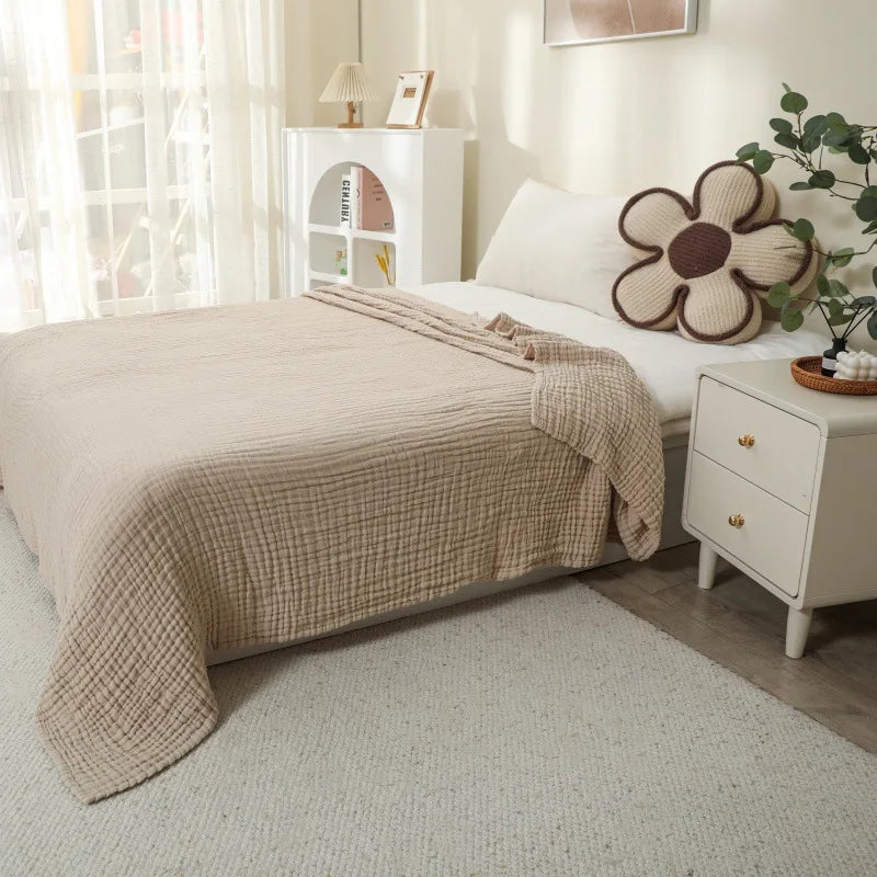 Beige gesteppte Decke über weißes Bett neben Nachttisch mit Blumen-Dekoration