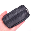 A black leather compact zippered coin purse with a metal key holder is held in a hand.