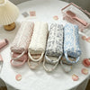 A collection of quilted cotton hair dryer storage bags in various floral patterns are displayed on a white tablecloth.