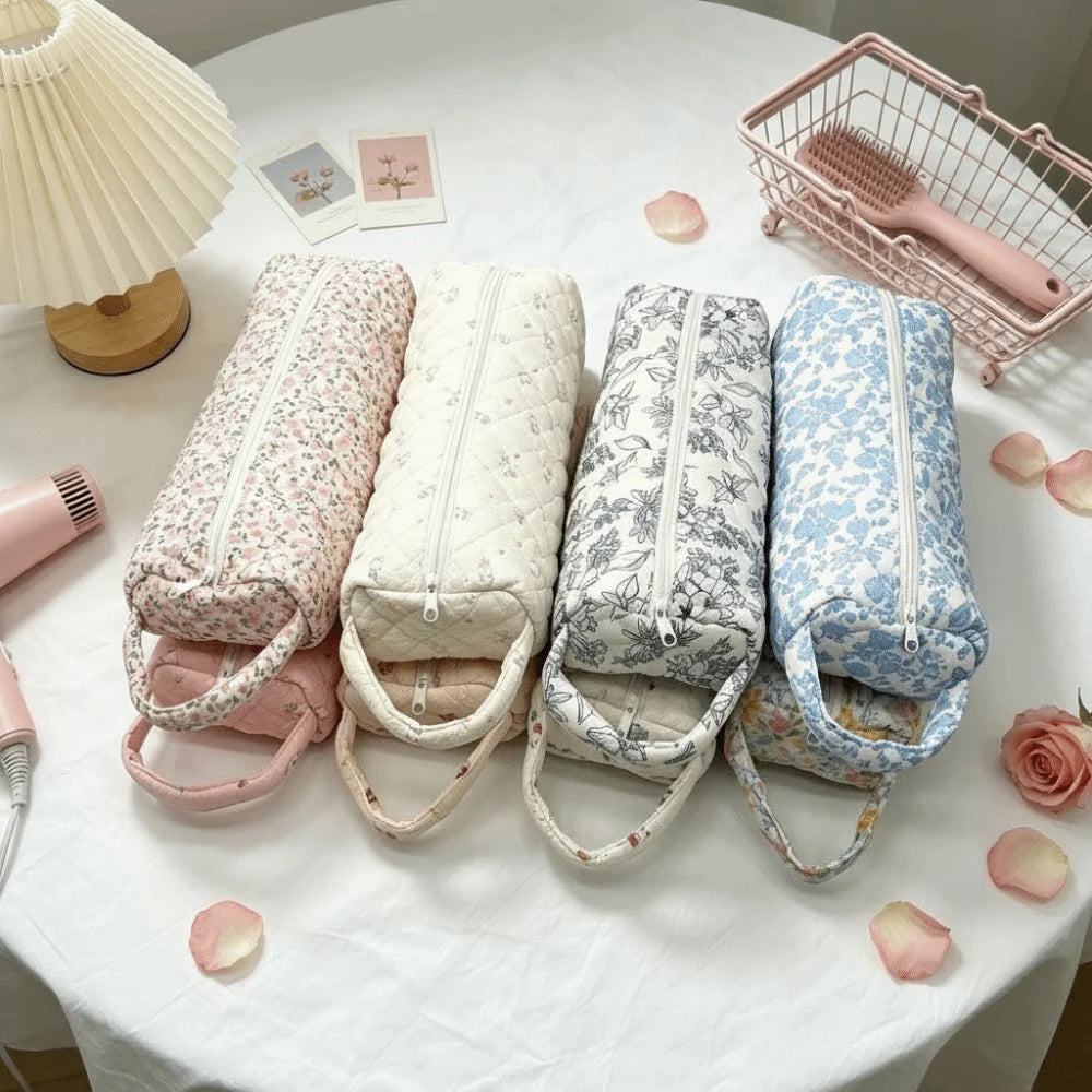 A collection of quilted cotton hair dryer storage bags in various floral patterns are displayed on a white tablecloth.