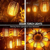 A set of solar torch lights with dancing flame patterns illuminating garden and pathway decorations.