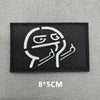 Black embroidered patch featuring a stylized, grinning face design on a gray background.
