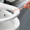 A hand is using a silicone toilet seat lifter with a pull ring to lift a white toilet seat.