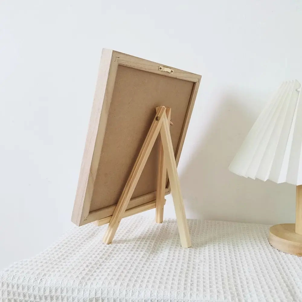 Una pizarra de fieltro con un marco de madera clara apoyada contra una pared blanca.