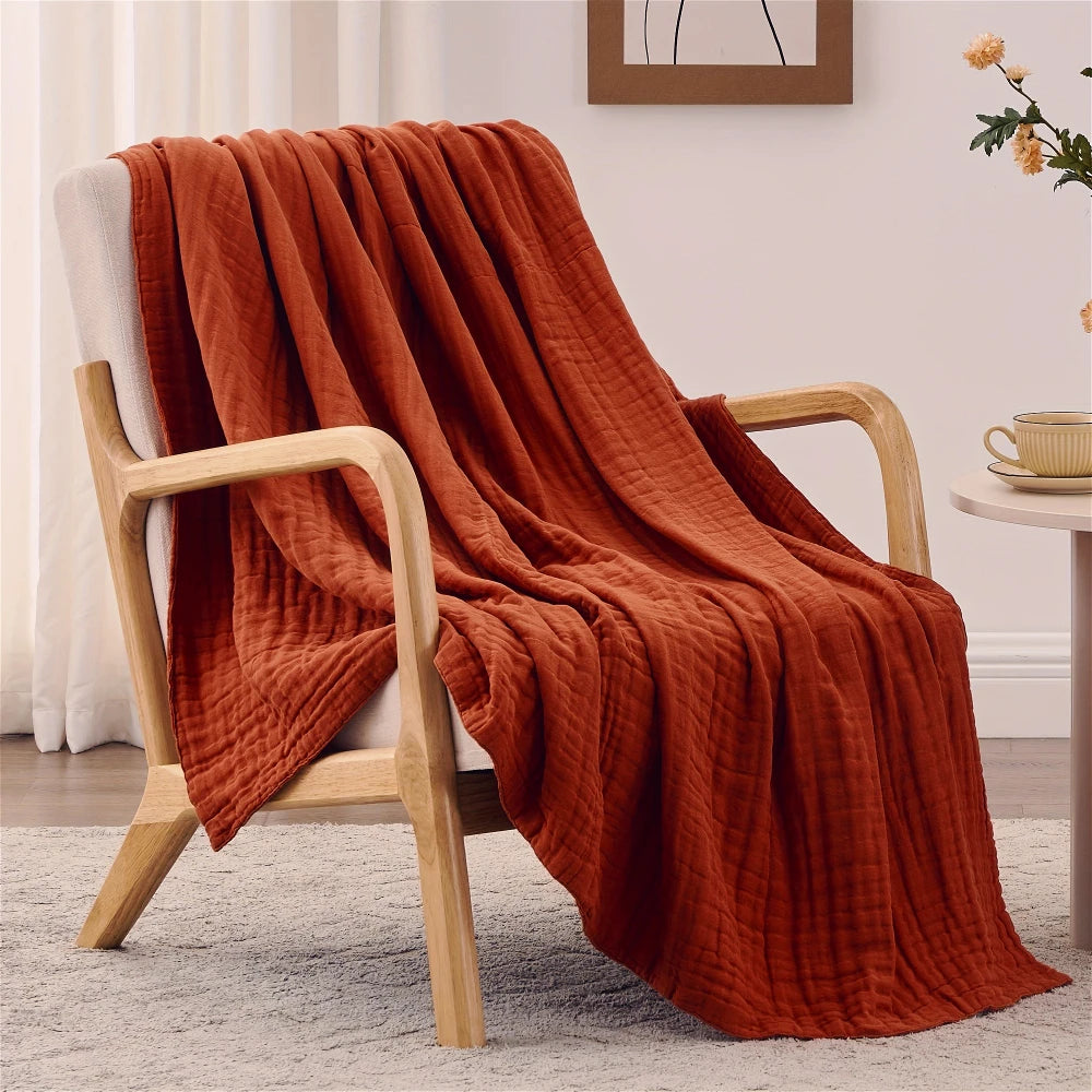 Terrakotta-orange gewebte Decke über einem hellen Holzstuhl.