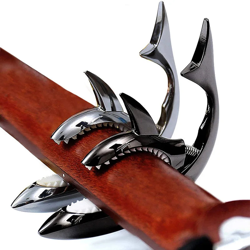 A close-up of a shark-design guitar capo with a zinc alloy build mounted on a wooden neck.