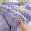 A hand is touching a fluffy purple fleece duvet cover with a rabbit design.