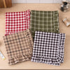 A collection of plaid fabric oven skirts in red, green, and brown tones with ruffled trims.