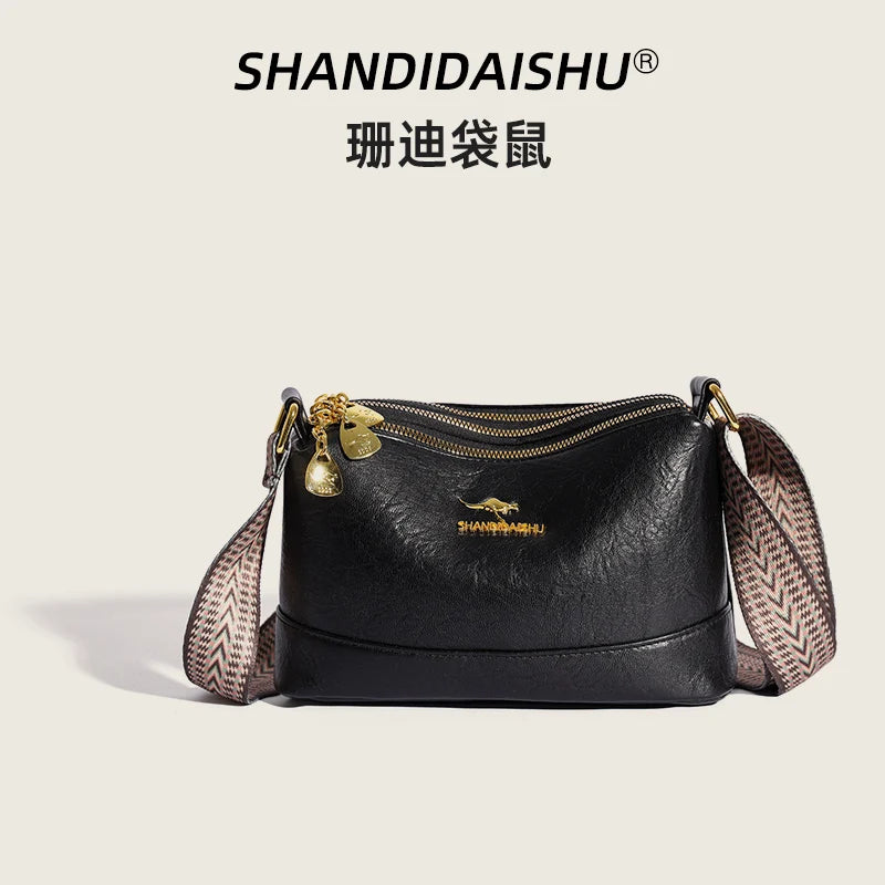 Black PU leather crossbody shoulder bag with gold hardware and patterned strap.