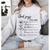 A woman wearing a light gray sweatshirt with black text that reads God says you are unique strong beautiful forgiven precious