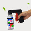 A hand holds a black ergonomic spray paint gun handle, positioned above an aerosol can with colorful paint dots.