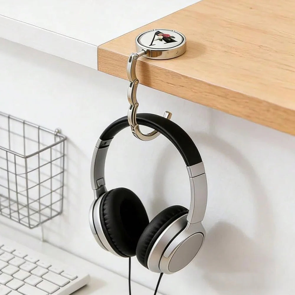 Eine silberne Briefhakenhake ist auf einem Holzregal befestigt und hält ein Paar schwarze Over-Ear-Kopfhörer.