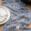 Gray crinkle gauze fabric draped as a table runner with white plates and cutlery.