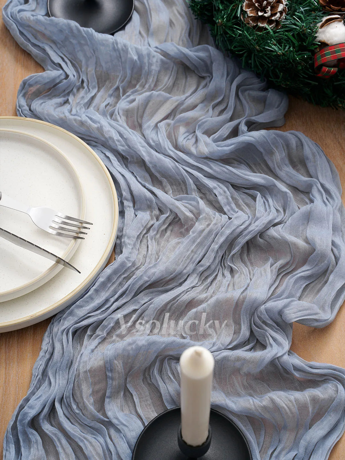 Gray crinkle gauze fabric draped as a table runner with white plates and cutlery.