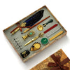 A wooden box holds a vintage calligraphy fountain pen set with various tools including a wax seal stamp kit.