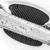 Close-up of a carbon fiber car door handle protected by a clear film, showing water droplets on the surface.