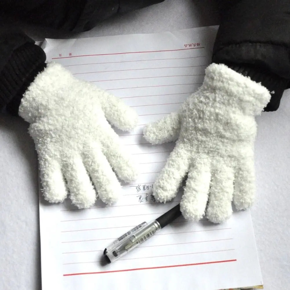 A pair of white, fluffy plush winter gloves resting on a lined piece of paper.