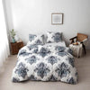 White duvet cover set with blue and gray floral geometric pattern displayed on a bed against a white wall.