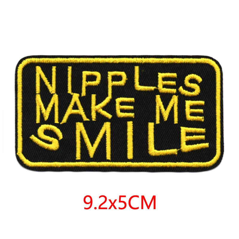 Black embroidered iron-on letter patch with yellow stitching that reads Nipples Make Me Smile
