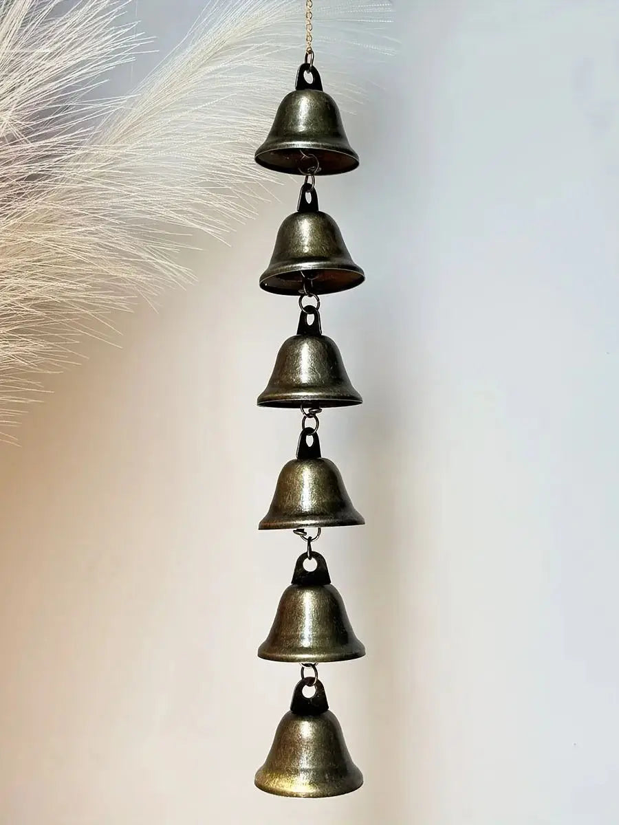 Cinq carillons à vent en bronze antiques, disposés verticalement et suspendus à une chaîne sur fond blanc.