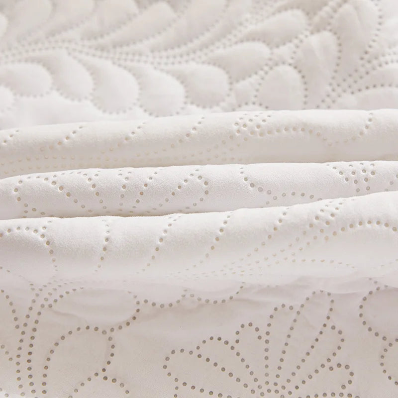White waterproof quilted mattress protector with decorative perforations and extra padding.