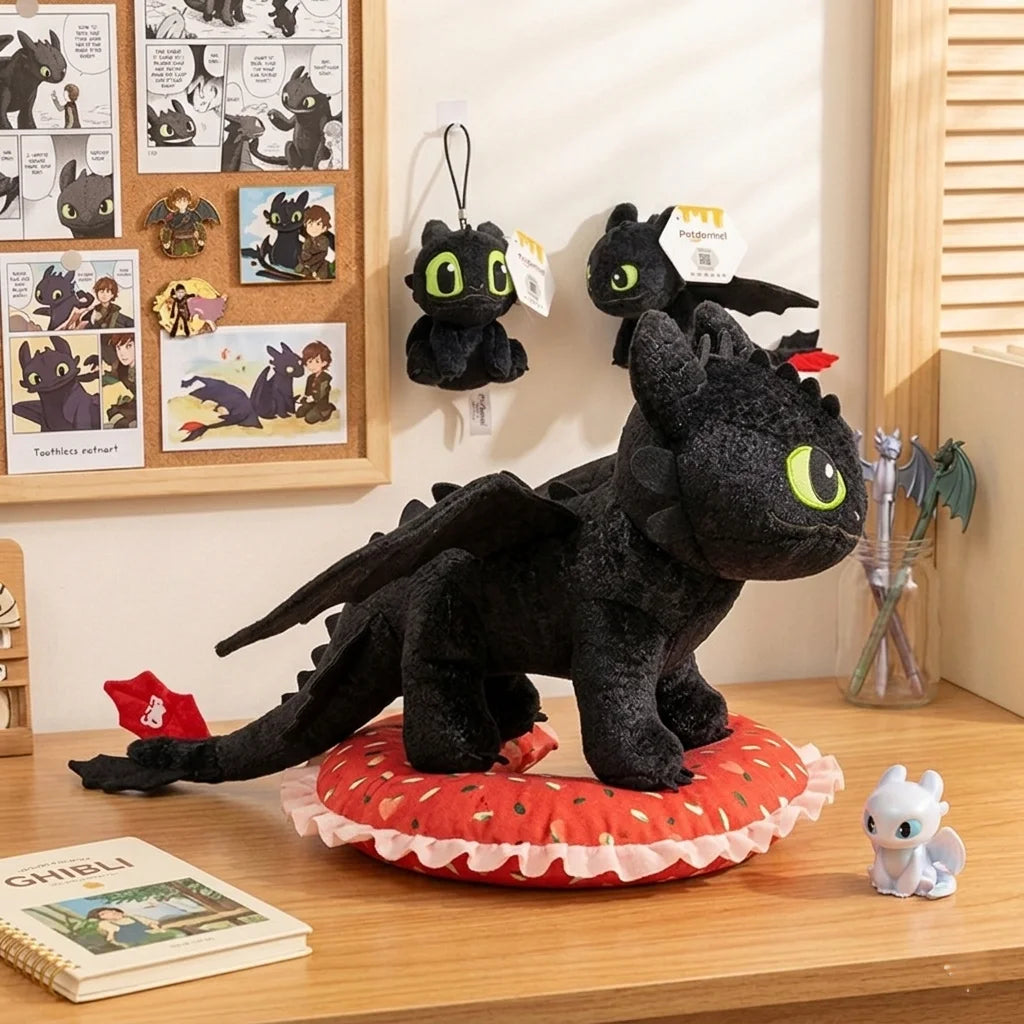 A black soft plush dragon toy resembling a Night Fury is displayed on a wooden surface.