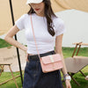 A woman wearing a white t-shirt and denim skirt holds a pink compact crossbody handbag.