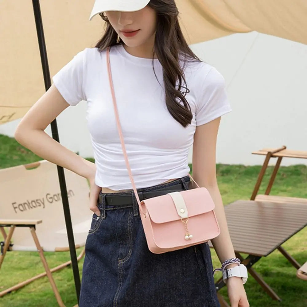 A woman wearing a white t-shirt and denim skirt holds a pink compact crossbody handbag.
