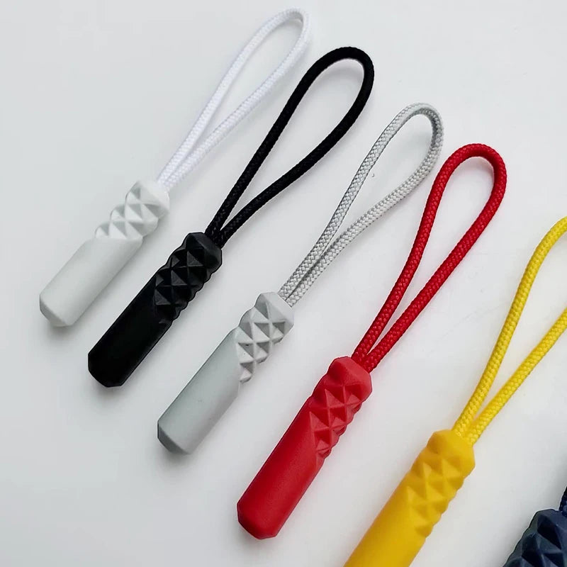 A collection of replacement zipper pulls with nylon cords in various colors including white, black, silver, red, and yellow.