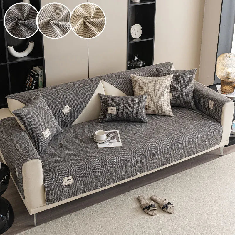 Canapé gris moderne avec des coussins beige clair et un petit livre blanc sur l'assise.