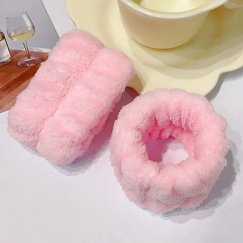 Pink microfiber wrist sweatband and scrunchies for face washing displayed on a white surface.