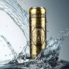 A gold-colored mini electric razor is shown splashing water in a dynamic shot.