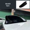 Black shark fin antenna cover for a white car roof.