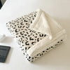 A leopard print plush jacquard throw blanket folded on a white surface.