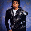 A portrait of a man with dark hair wearing a black leather jacket and white shirt against a blue mottled background.