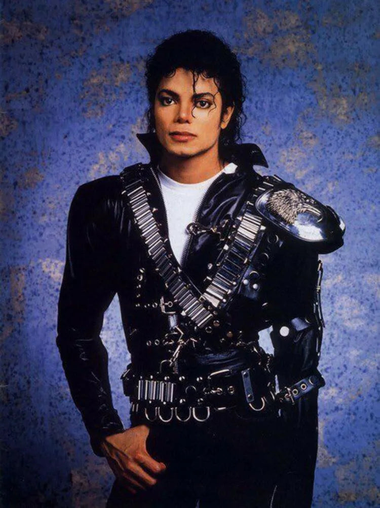 A portrait of a man with dark hair wearing a black leather jacket and white shirt against a blue mottled background.