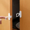 A hand is using a white silicone toilet lid lifter with a self-adhesive hook to open a wooden cabinet door.