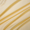 A close-up of a cream-colored luxury bamboo flat sheet draped in soft, flowing folds.