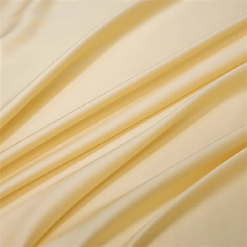 A close-up of a cream-colored luxury bamboo flat sheet draped in soft, flowing folds.