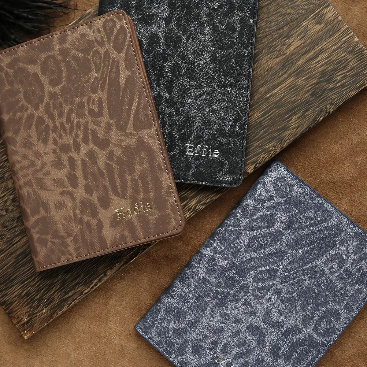 A stack of custom leopard print passport holders in brown and gray tones with personalized embossing.