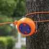 An orange retractable clothesline with a purple base is clipped to a tree trunk.