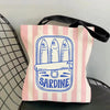 A pink striped canvas tote bag featuring a blue line drawing of a sardine and a fish bone.