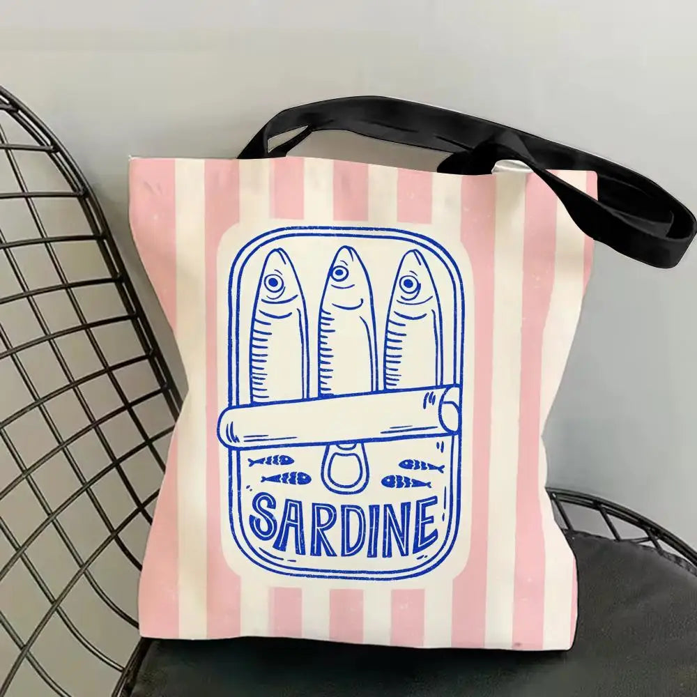 A pink striped canvas tote bag featuring a blue line drawing of a sardine and a fish bone.