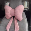 A pink butterfly bow tie neck pillow with a matching fabric cover is shown in a car seat context.